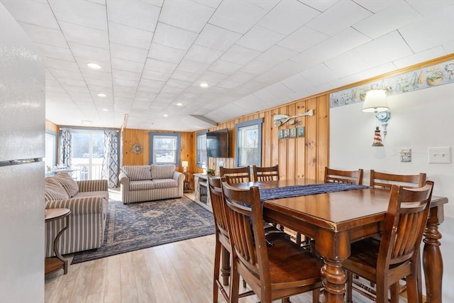 dining space with light hardwood / wood-style floors and wood walls