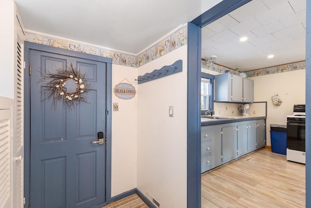 interior space with white gas range, sink, and light wood-type flooring