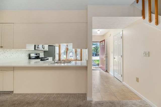 19 Garden St Unit 107, Danvers, MA 01923 - kitchen with appliances with stainless steel finishes, a peninsula, light tile patterned flooring, light countertops, and light carpet