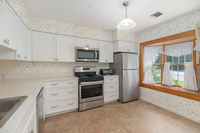 19 Garden St Unit 107, Danvers, MA 01923 - kitchen with appliances with stainless steel finishes, wallpapered walls, light countertops, white cabinetry, and hanging light fixtures