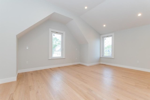 additional living space featuring healthy amount of natural light, vaulted ceiling, light wood-type flooring, recessed lighting, and baseboards