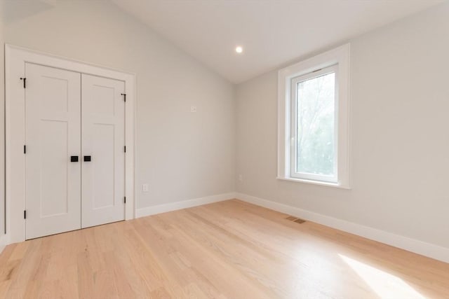 unfurnished bedroom with light wood-style flooring, vaulted ceiling, baseboards, a closet, and recessed lighting