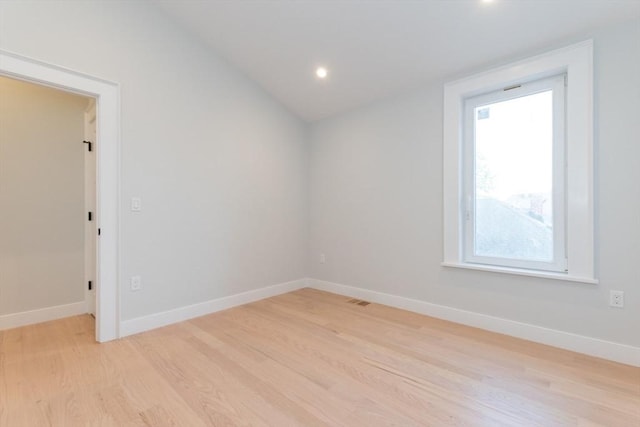empty room featuring light wood-style floors, healthy amount of natural light, baseboards, lofted ceiling, and recessed lighting