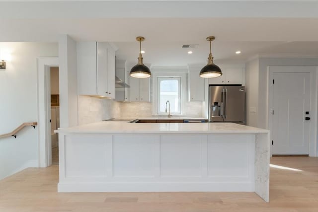 kitchen featuring high end refrigerator, light countertops, a peninsula, decorative backsplash, and white cabinets
