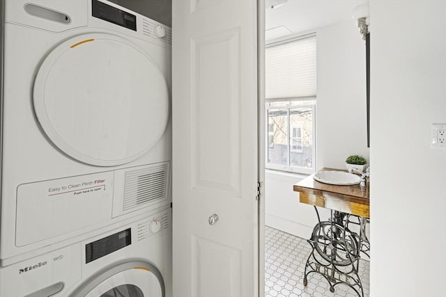 laundry room with stacked washer / drying machine and sink