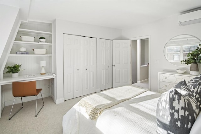 carpeted bedroom featuring an AC wall unit and multiple closets