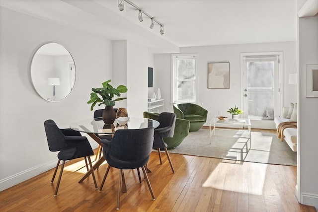 dining space with rail lighting and light hardwood / wood-style flooring