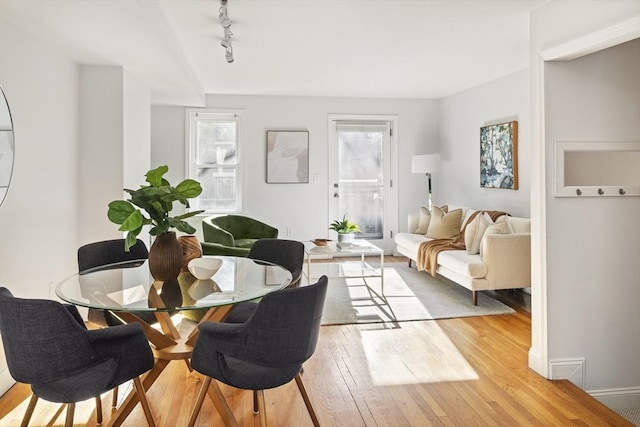 dining space featuring a healthy amount of sunlight, light wood-type flooring, and rail lighting