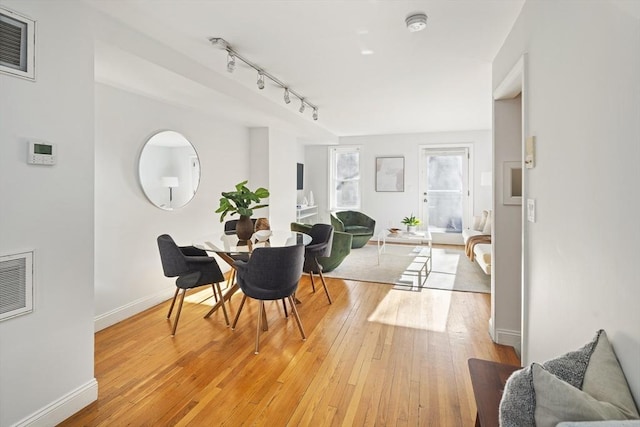 dining space featuring rail lighting and light hardwood / wood-style floors