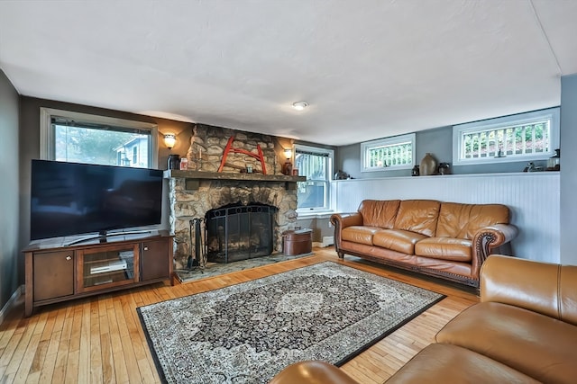 living room with light wood-type flooring and a stone fireplace