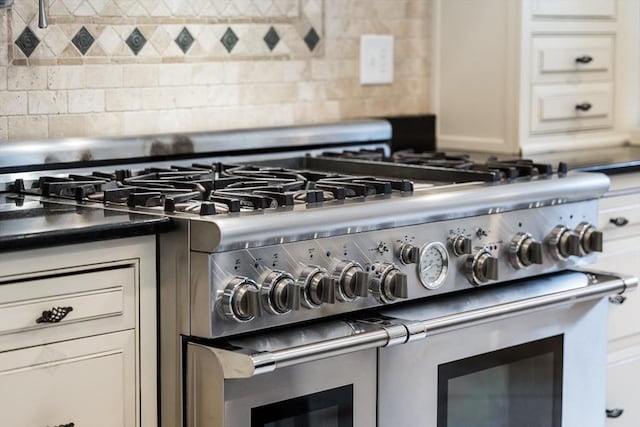 details with high end stove, decorative backsplash, and white cabinets