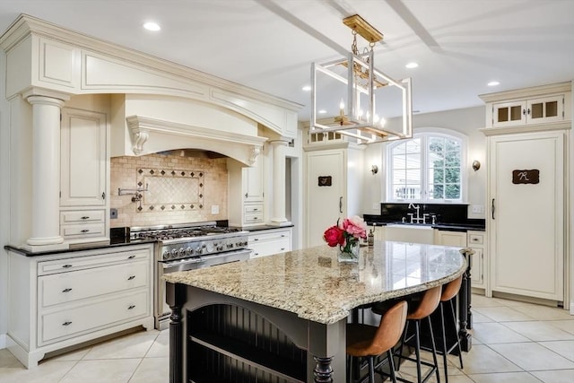 kitchen featuring ornate columns, stainless steel range, a center island, tasteful backsplash, and pendant lighting