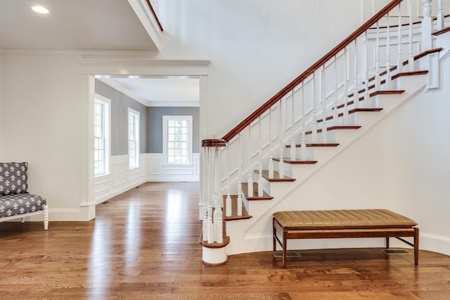 stairway with wood-type flooring and ornamental molding