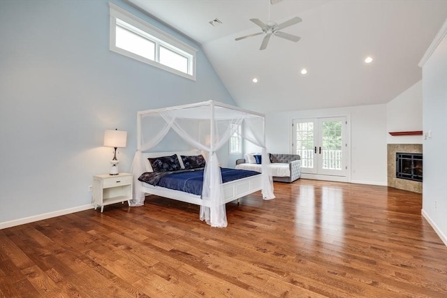 bedroom featuring hardwood / wood-style flooring, ceiling fan, lofted ceiling, and a tiled fireplace