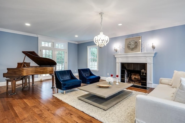 living room featuring crown molding, a chandelier, a fireplace, and wood-type flooring