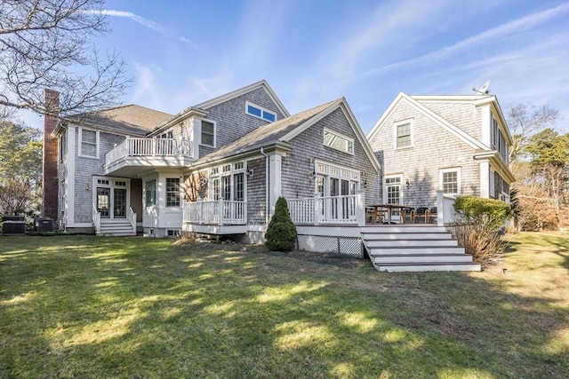 rear view of property with a wooden deck, a yard, and a balcony