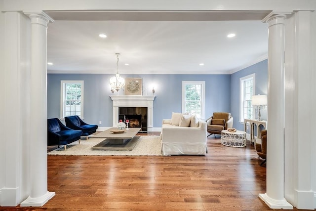 living room featuring a tile fireplace, wood-type flooring, ornamental molding, and a notable chandelier