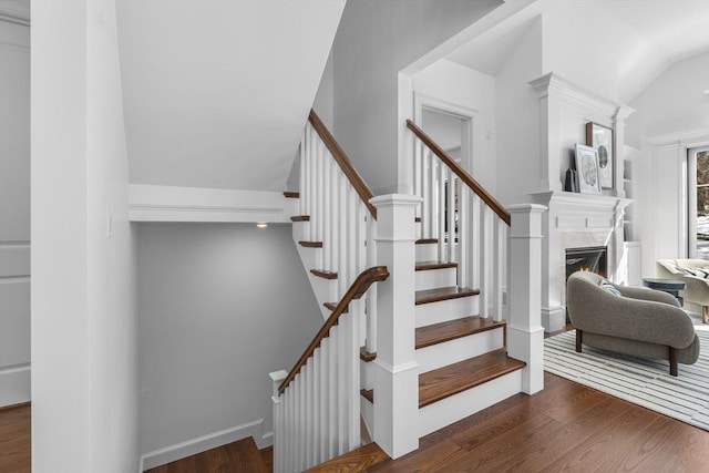 stairs featuring vaulted ceiling, wood finished floors, and a high end fireplace