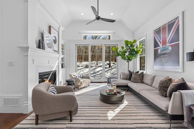 living room featuring a fireplace, visible vents, ceiling fan, vaulted ceiling, and wood finished floors