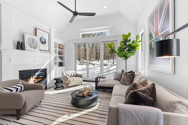 living area with built in shelves, a healthy amount of sunlight, vaulted ceiling, and a premium fireplace