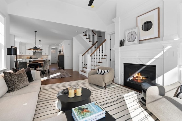 living area featuring a fireplace, recessed lighting, light wood-style flooring, stairway, and vaulted ceiling