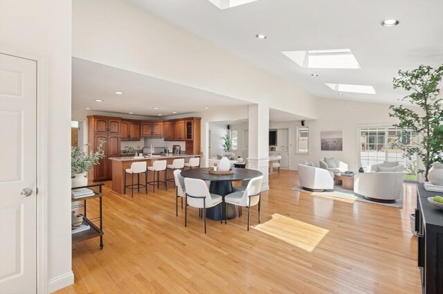 dining room featuring recessed lighting, vaulted ceiling with skylight, and light wood-type flooring