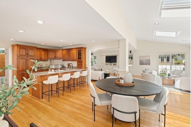 dining space featuring recessed lighting, vaulted ceiling with skylight, and light wood-type flooring