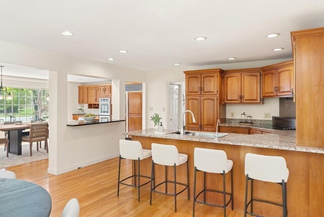 kitchen featuring a peninsula, a kitchen breakfast bar, a sink, and light wood-style flooring