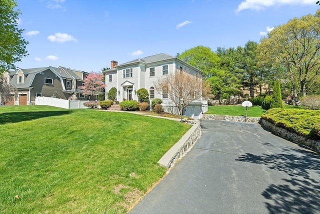 view of front of house featuring fence, a residential view, a front yard, a chimney, and driveway