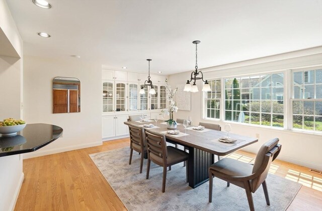 dining space with baseboards, recessed lighting, light wood finished floors, and a chandelier