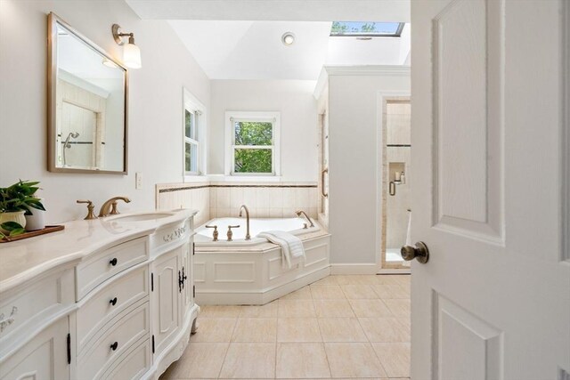 bathroom with a garden tub, vanity, tile patterned floors, a shower stall, and a skylight