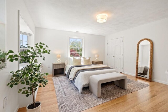bedroom featuring light wood-type flooring, baseboards, and a closet