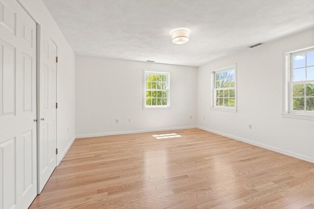 unfurnished room with baseboards, visible vents, plenty of natural light, and light wood-type flooring