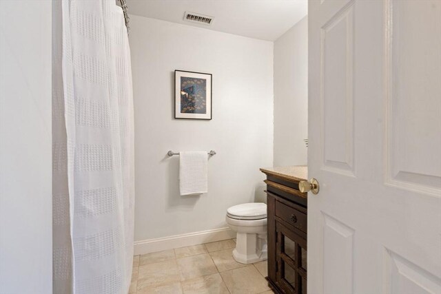 bathroom featuring visible vents, vanity, toilet, baseboards, and tile patterned floors