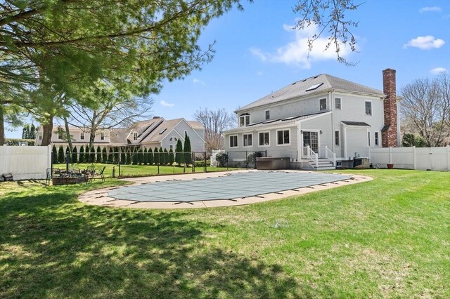 back of property featuring a fenced backyard, a chimney, cooling unit, a patio area, and a lawn
