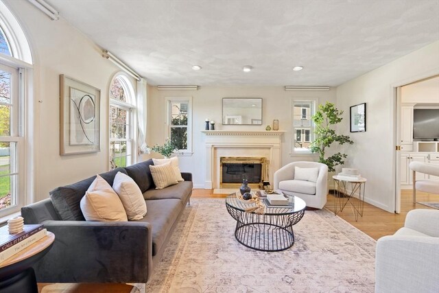 living room with recessed lighting, a fireplace with flush hearth, baseboards, and wood finished floors