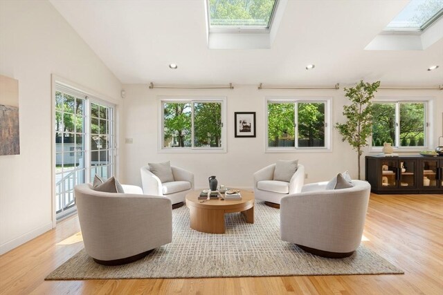 living area with baseboards, recessed lighting, wood finished floors, and vaulted ceiling with skylight