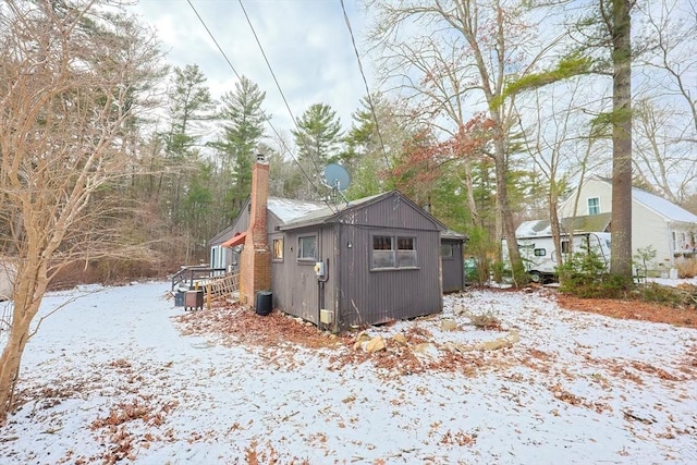 view of snow covered exterior with an outbuilding and central AC