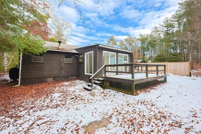 snow covered back of property featuring a wooden deck