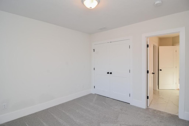 unfurnished bedroom with a closet and light carpet