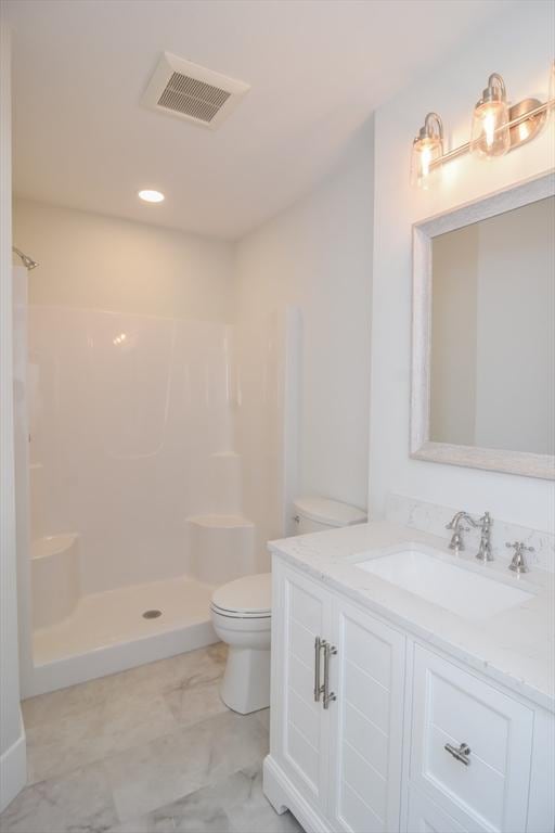 bathroom with walk in shower, vanity, and toilet