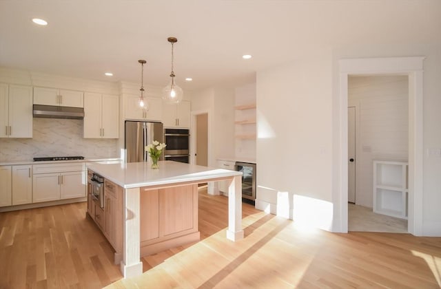 kitchen with hanging light fixtures, tasteful backsplash, a kitchen island, white cabinets, and appliances with stainless steel finishes