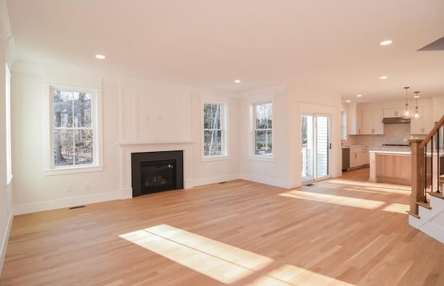 unfurnished living room featuring plenty of natural light and light hardwood / wood-style flooring