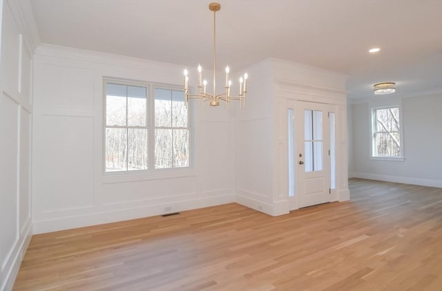 unfurnished dining area featuring light hardwood / wood-style flooring and an inviting chandelier