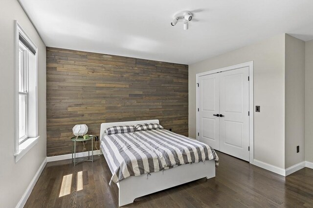 122 Green St, Northborough, MA 01532 - bedroom with baseboards, wood walls, wood finished floors, an accent wall, and a closet