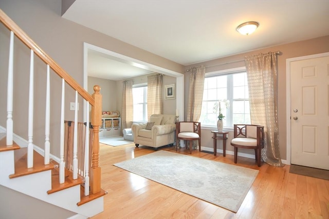 sitting room with stairway, light wood-style flooring, and baseboards