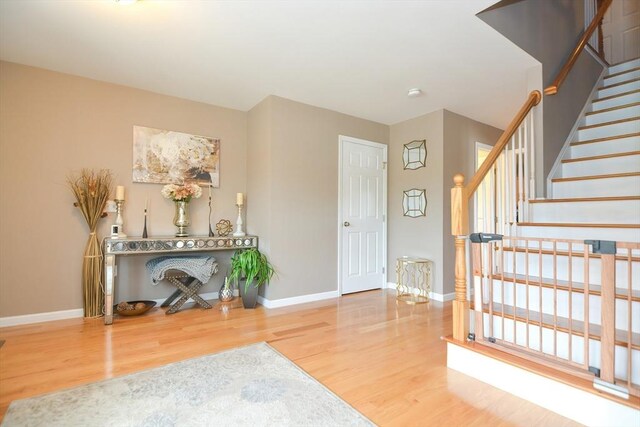 entryway featuring stairway, wood finished floors, and baseboards