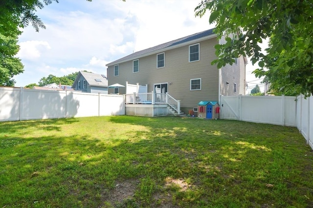 rear view of house with a fenced backyard and a yard