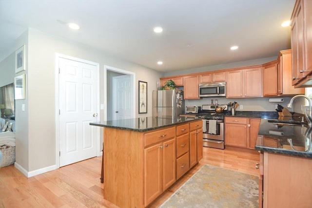 kitchen with recessed lighting, a sink, stainless steel appliances, light wood-style floors, and a center island