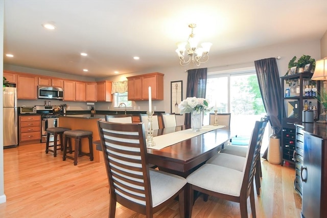 dining area with recessed lighting, light wood-style flooring, plenty of natural light, and an inviting chandelier